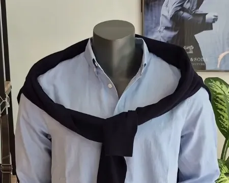 Detail eines Herren-Looks: dunkler Sweater lässig um die Schultern gebunden, darunter ein helles Hemd
